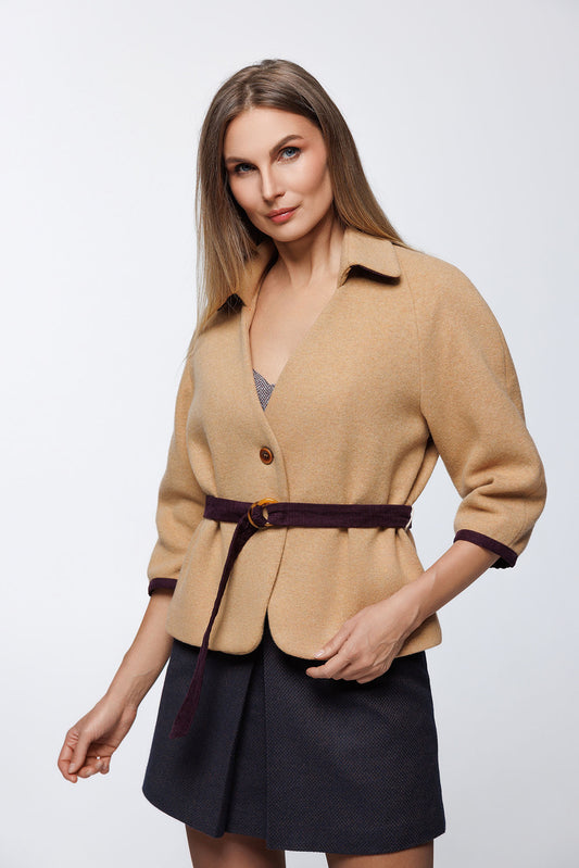 Three-quarter view highlighting the vibrant purple corduroy cuffs against the warm honey-beige wool fabric.