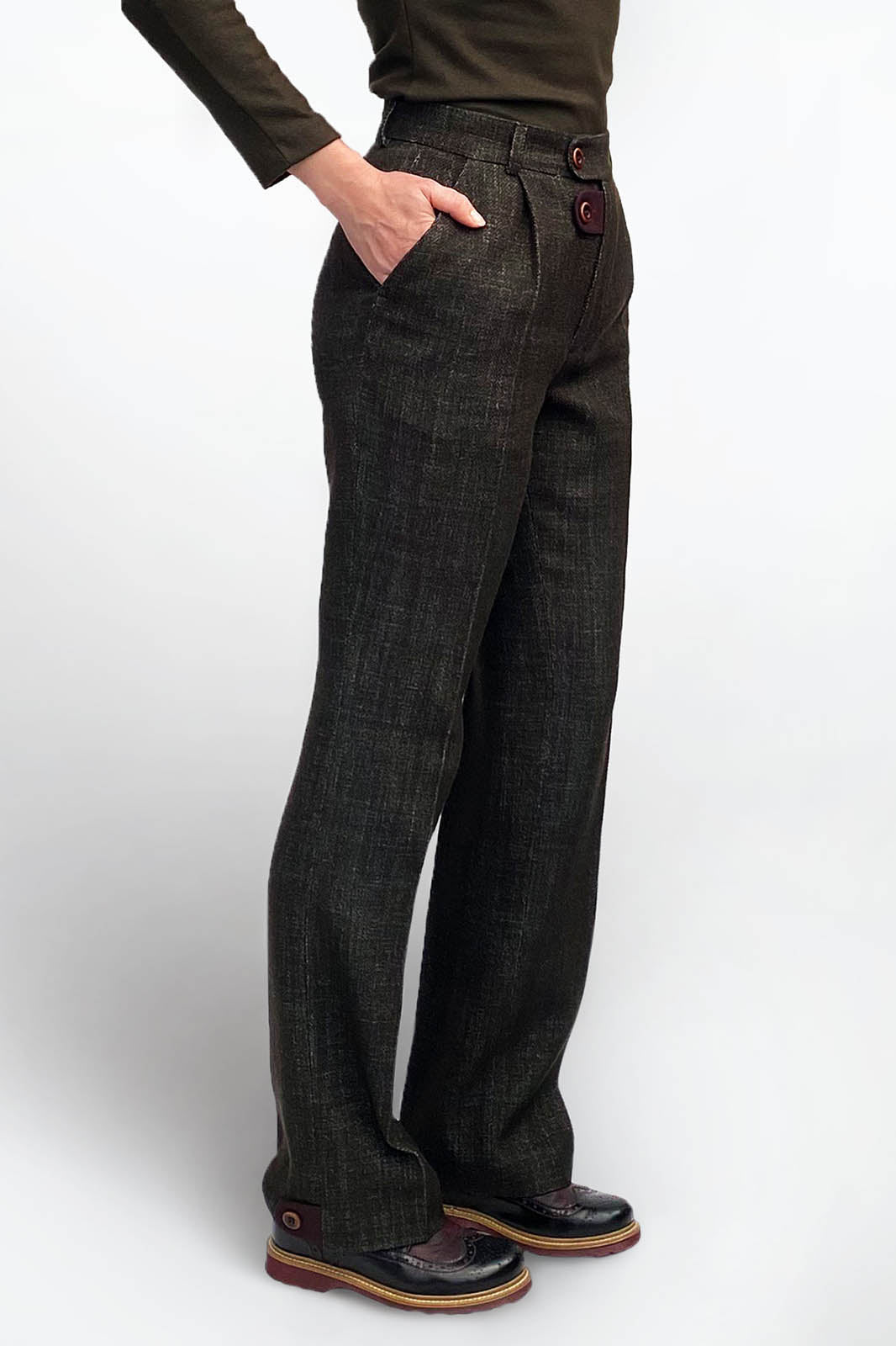 A three-quarter view of the deep olive trousers, showcasing the high-waisted fit and side pocket. The image highlights the structured straight-leg silhouette and the maroon contrast button detail at the front waistband.