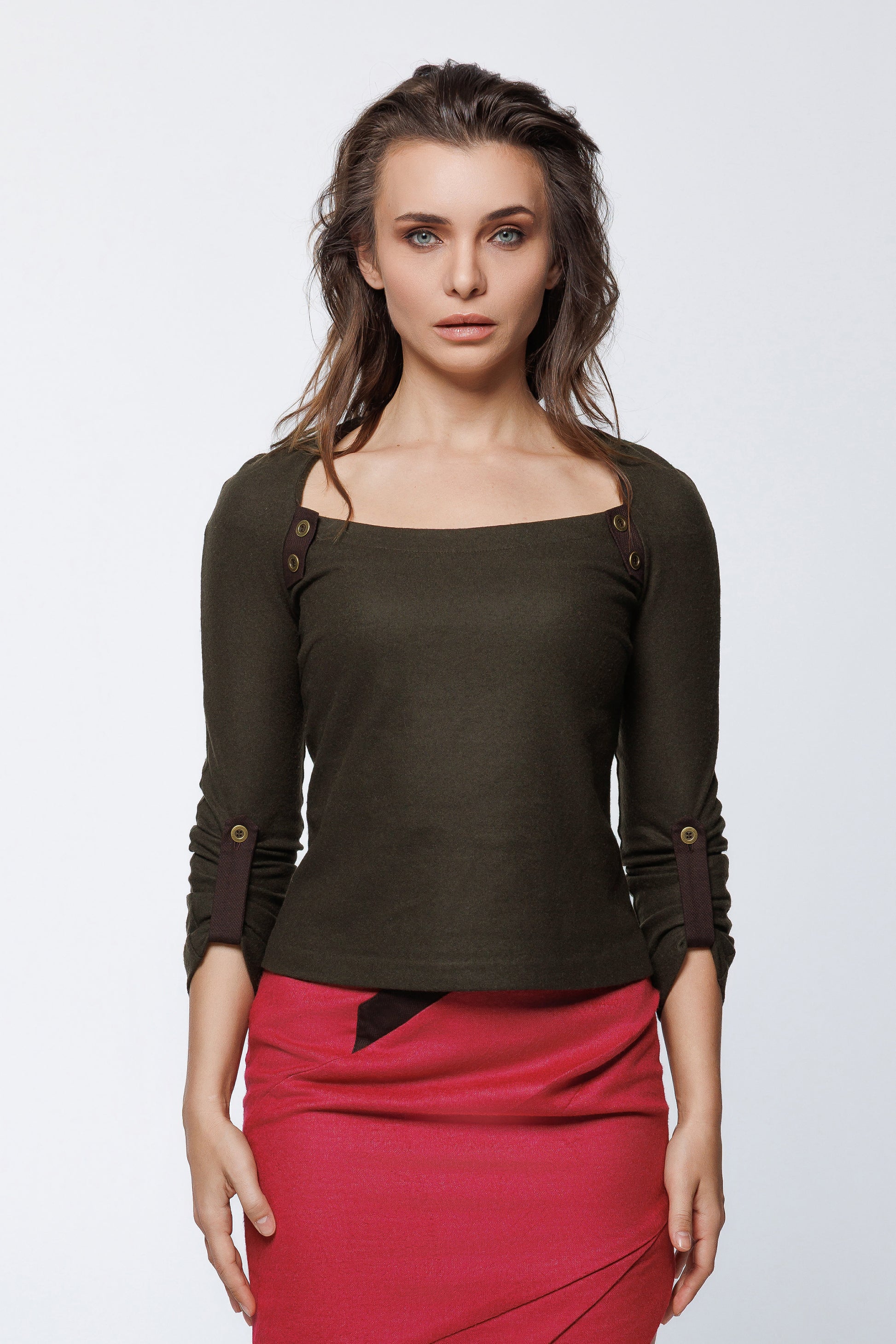 Woman wearing a dark green top with button details and a red skirt on a white background