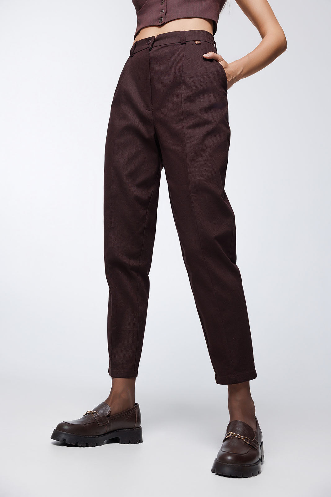 A low-angle shot of the trousers from the waist down, highlighting the ankle-length crop and the continuation of the vertical seams on the front and back of the legs.