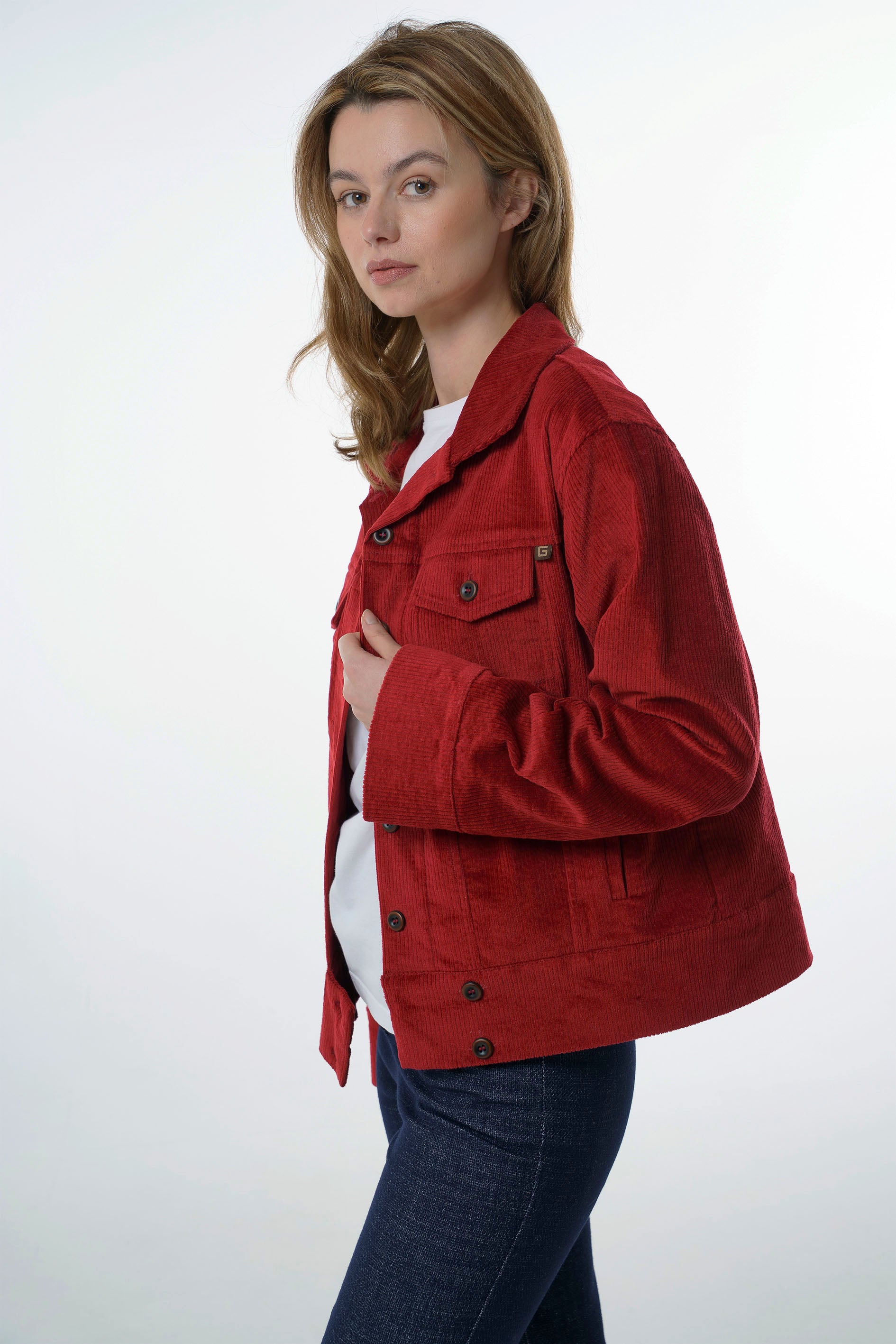 Three-quarter view of a woman wearing an open dark red corduroy jacket, highlighting the casual drape and versatile layering style.