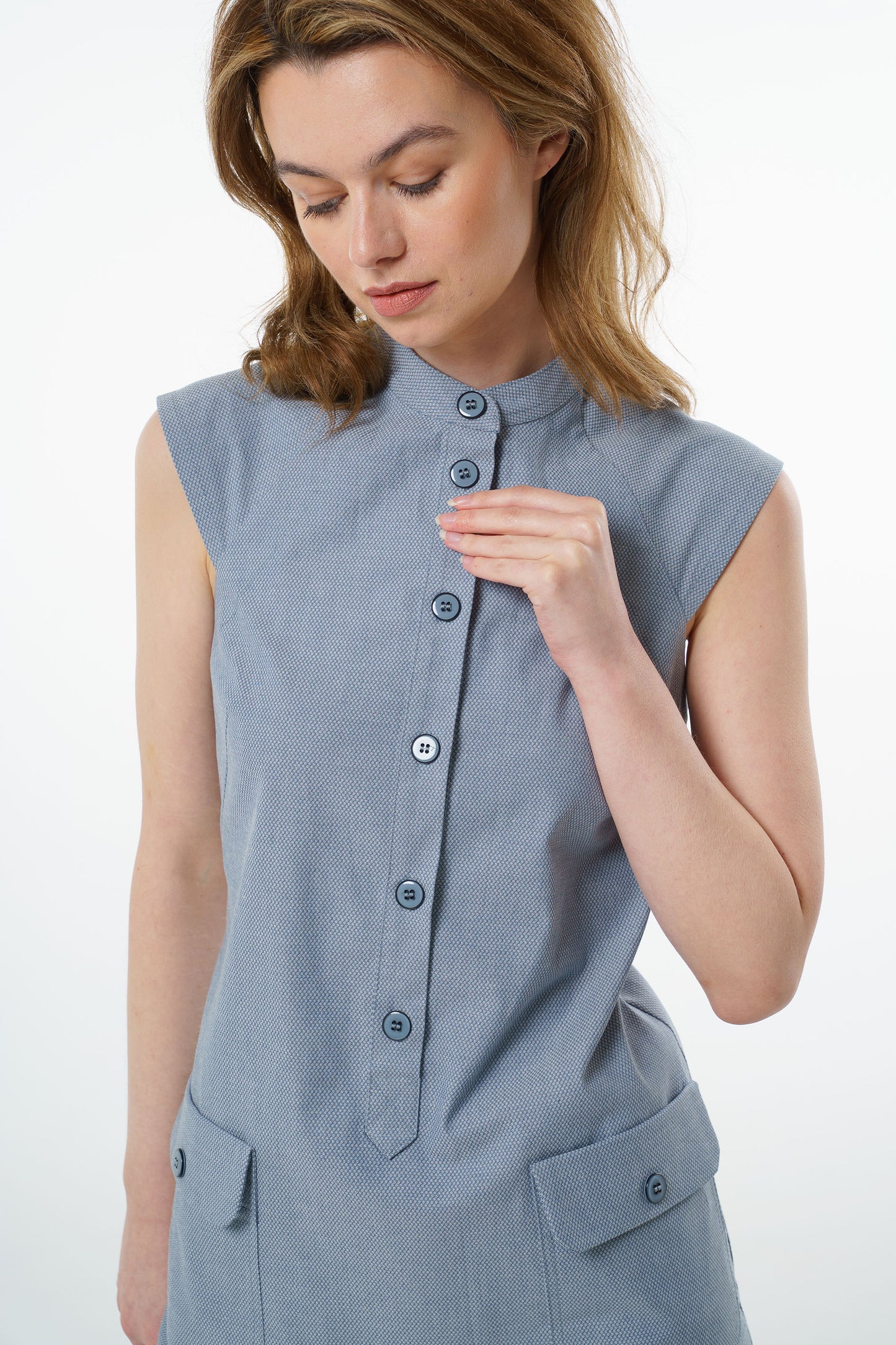 Close‑up of slate blue sleeveless cotton dress with mandarin collar, textured fabric, and button‑up placket.