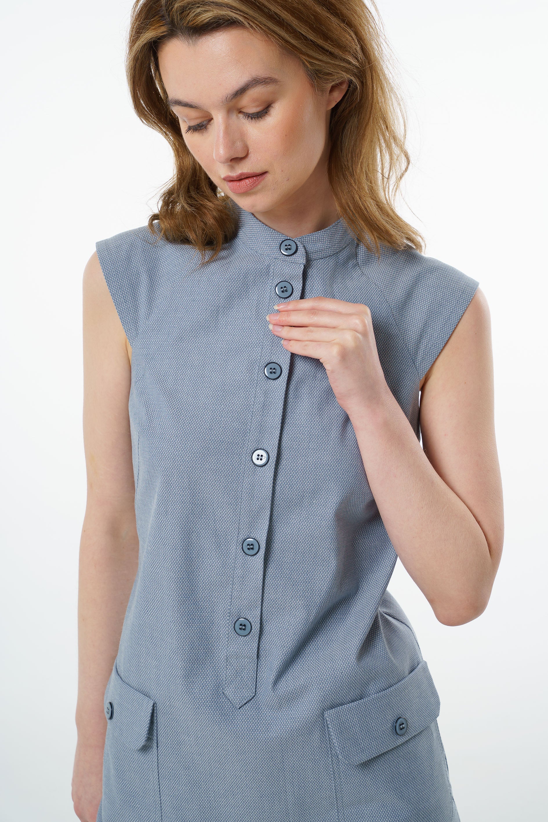 Close‑up of slate blue sleeveless cotton dress with mandarin collar, textured fabric, and button‑up placket.
