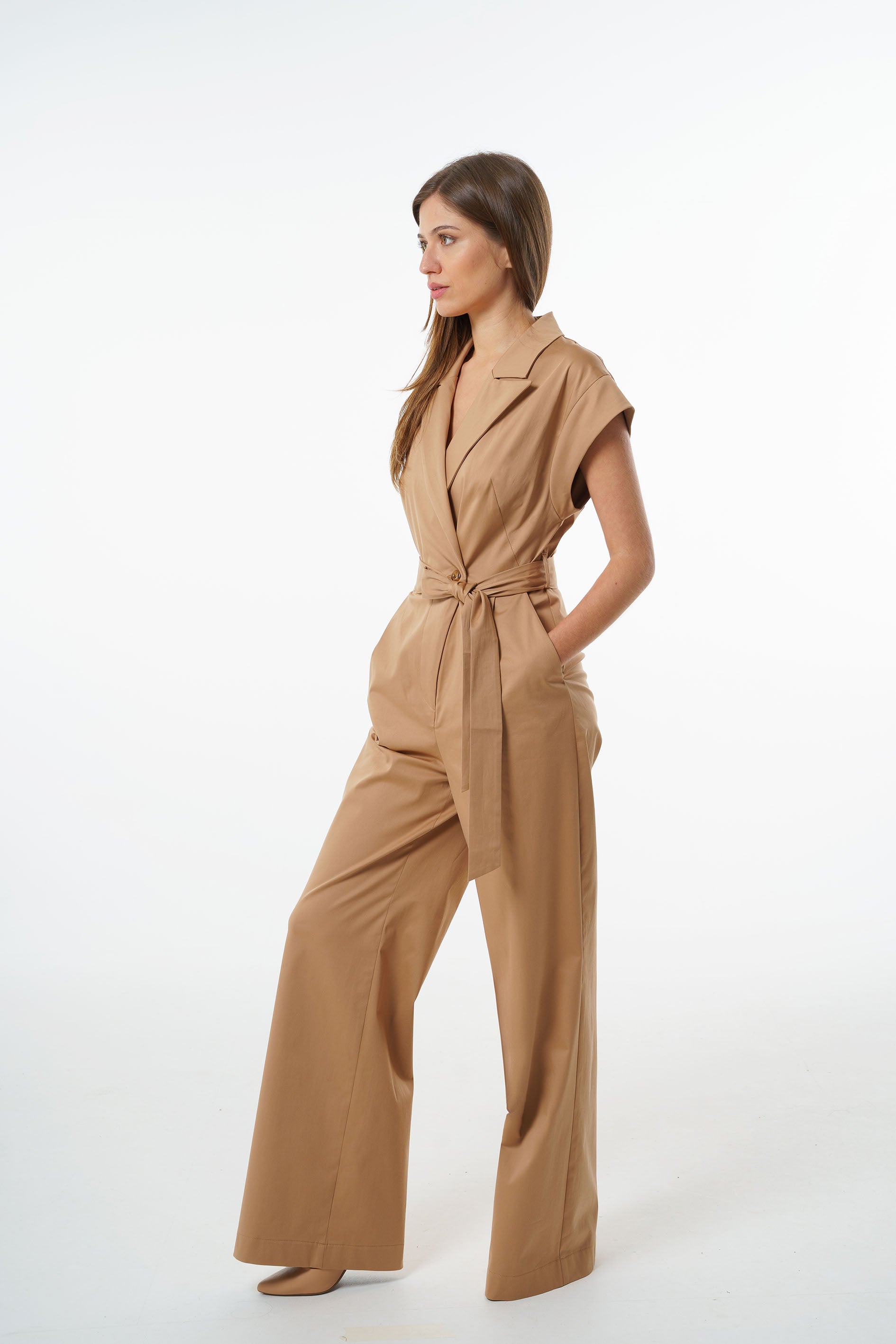 Camel cotton–viscose wrap‑front jumpsuit with wide‑leg trousers and a tied belt, worn by a model, angled studio view.