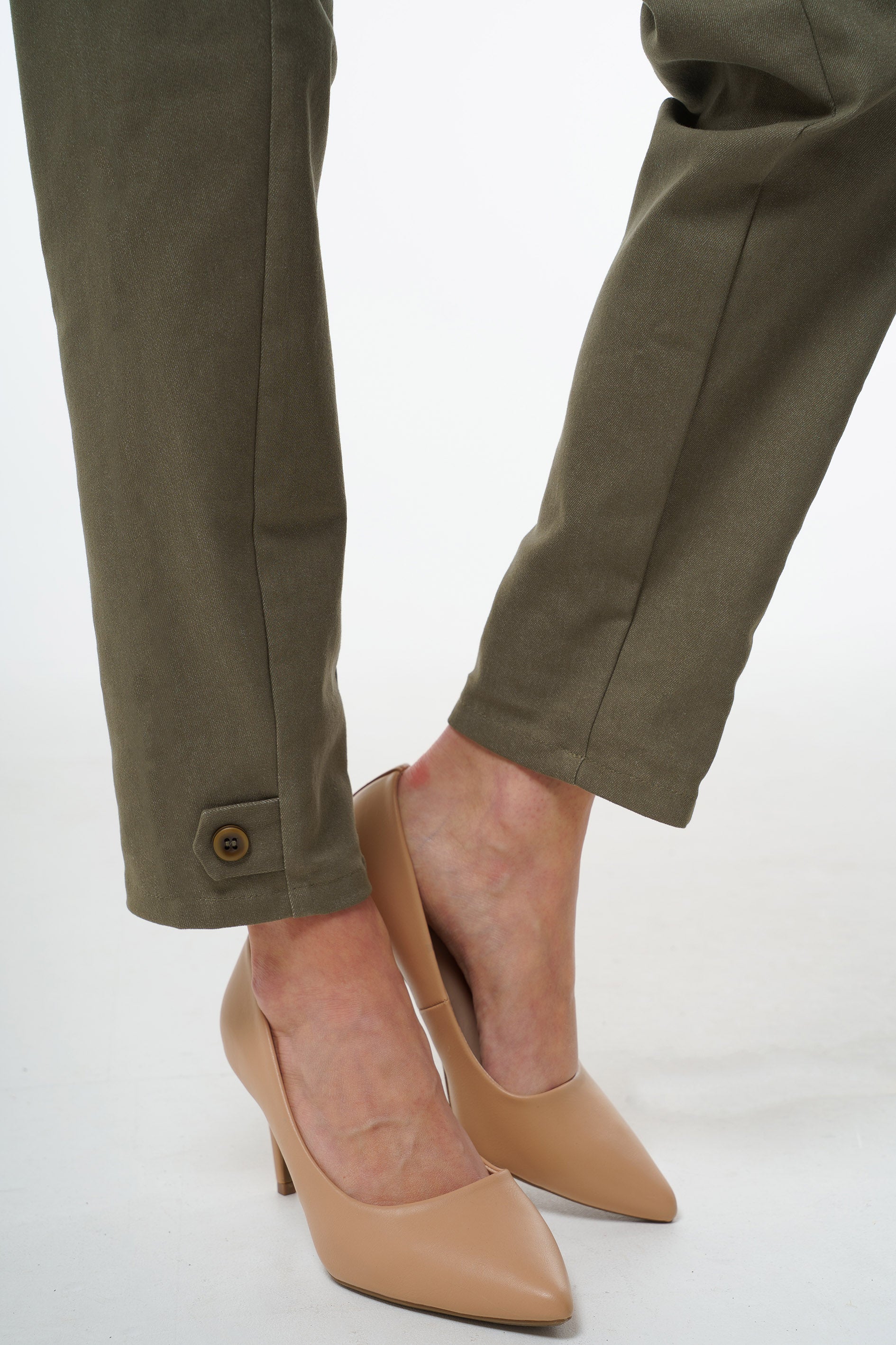 Close‑up of olive stretch denim trousers showing button‑accented ankle cuff and tailored hem, worn by a model.