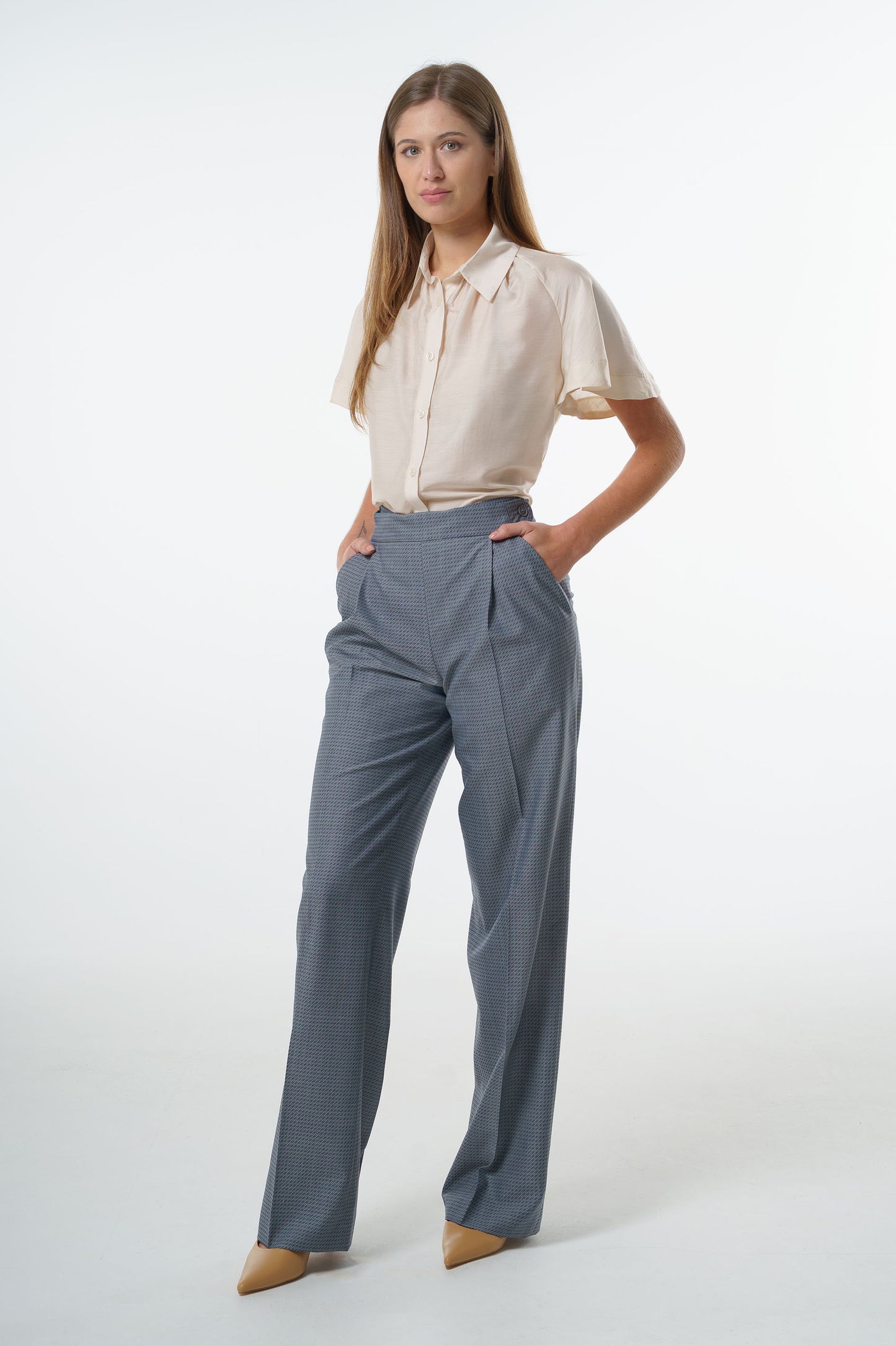 Mid‑waisted wide‑leg virgin wool trousers with an adjustable side‑button waistband and soft drape, worn by a model with a short‑sleeve blouse, front studio view.