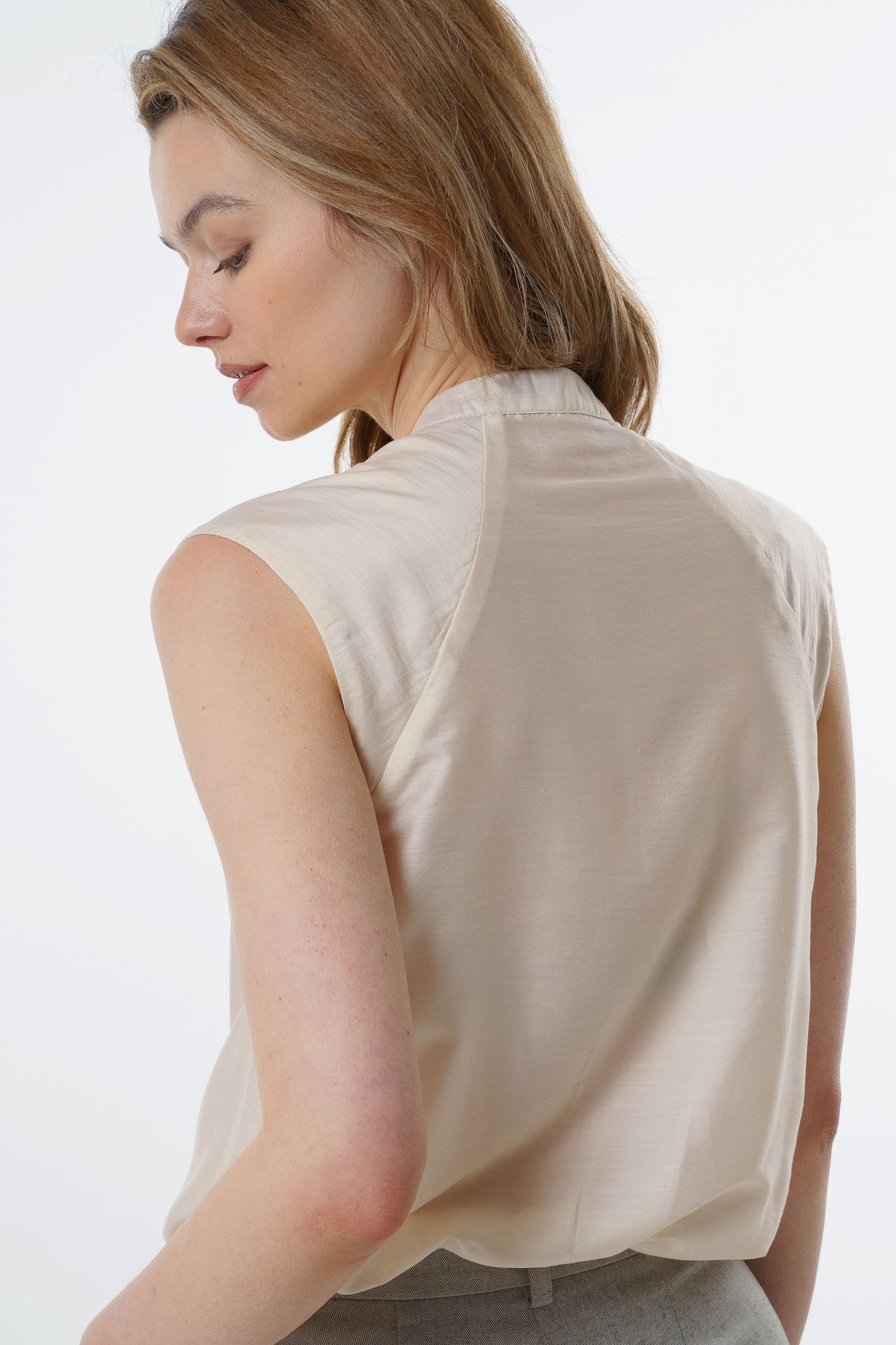 Ivory sleeveless silk–viscose blouse with back seam detailing and fluid drape, worn by a model, back studio view.