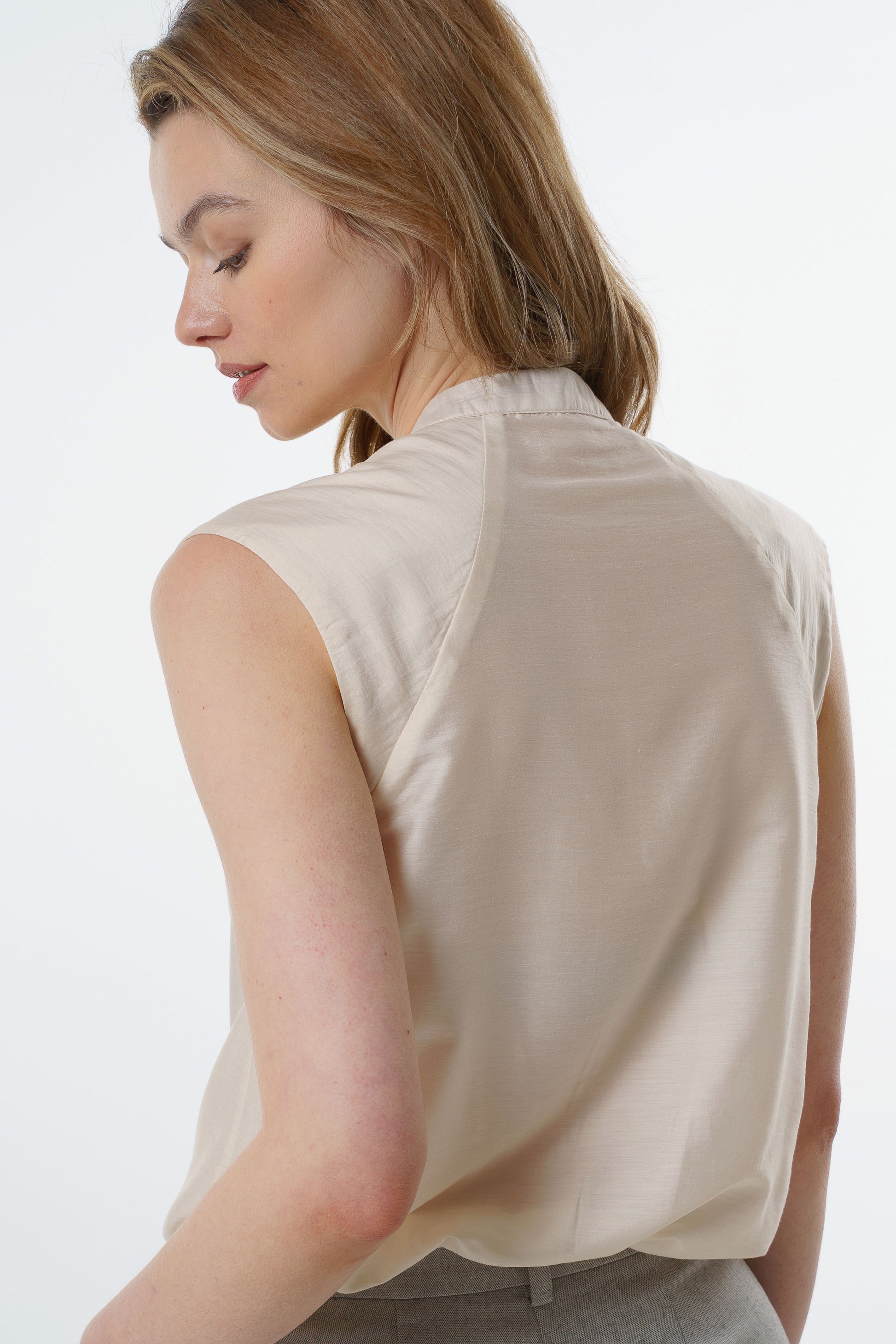 Ivory sleeveless silk–viscose blouse with back seam detailing and fluid drape, worn by a model, back studio view.