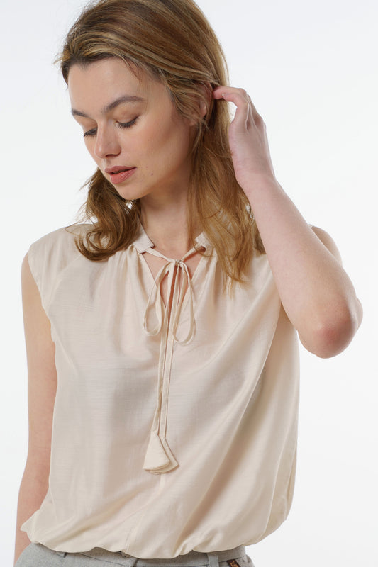 Ivory sleeveless silk–viscose blouse with front tie and soft drape, worn by a model, front studio view.