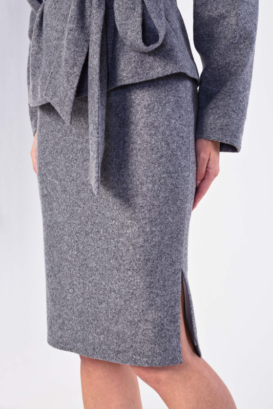 A close-up of a model wearing a gray textured skirt with a side slit and a matching gray tie belt jacket.