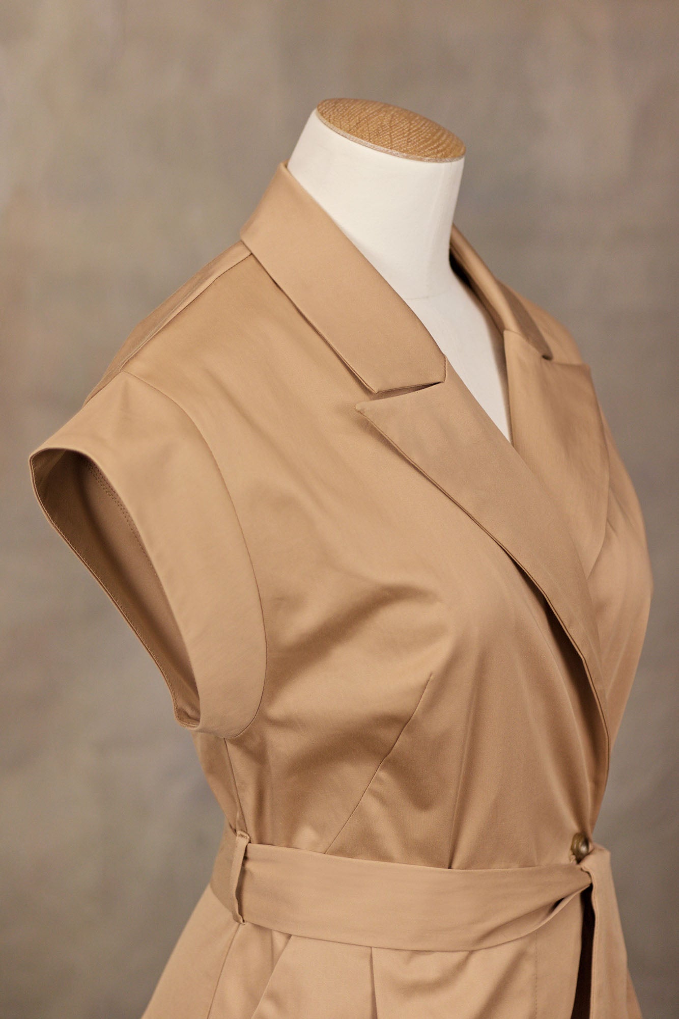 3/4 Close‑up of camel cotton–viscose wrap‑front jumpsuit showing notched collar, short sleeves, and tied waist, on a mannequin.