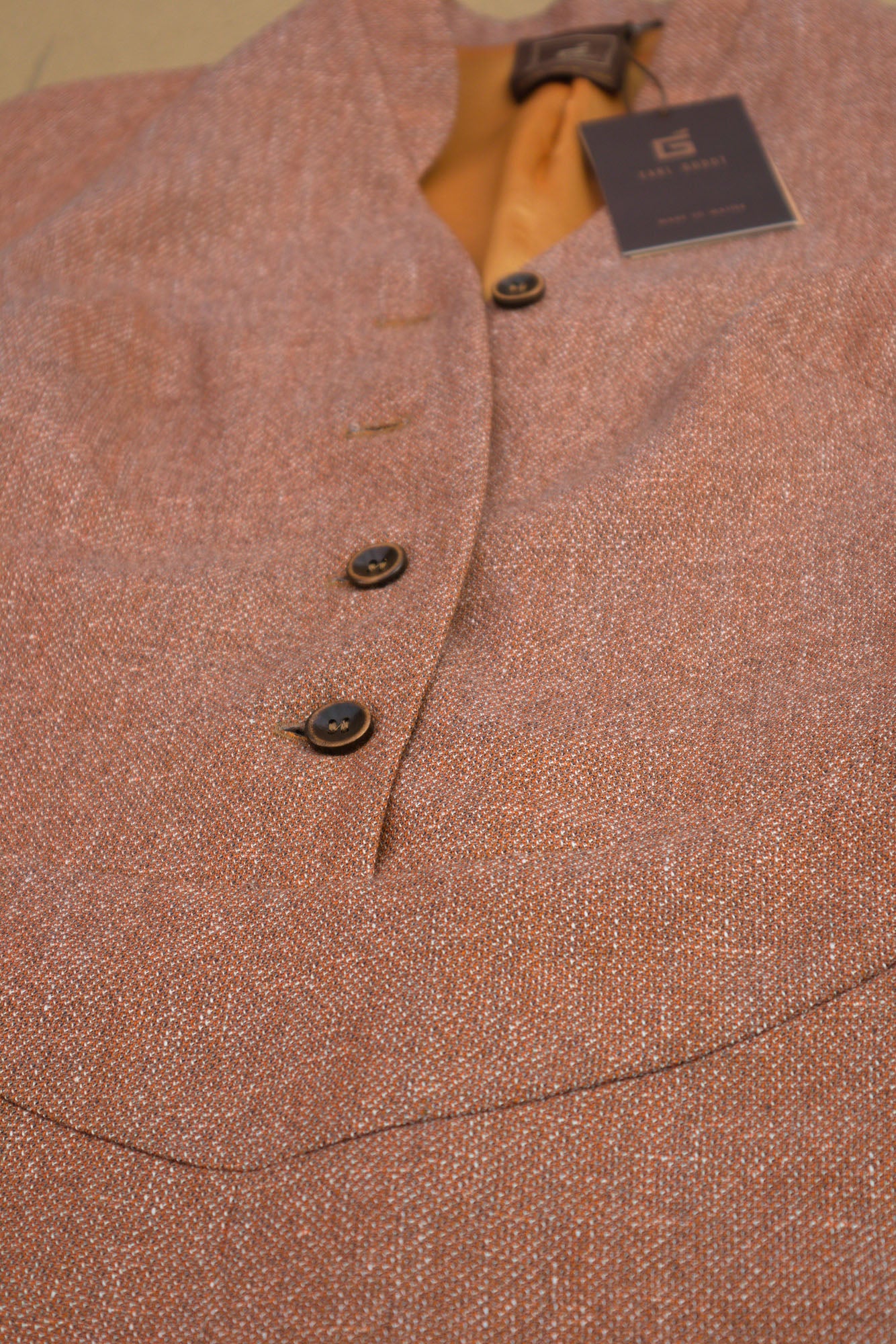 Macro view of a melange terracota coloured playsuit highlighting the fabtic texture, button fastening and solid orange viscose liing.