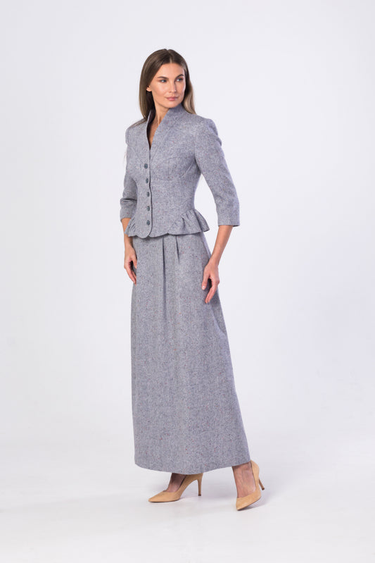 A woman modeling a light-blue-gray tweed two-piece set consisting of a cropped jacket with three-quarter sleeves and a matching high-waisted maxi skirt, paired with beige heels, against a plain white studio background.
