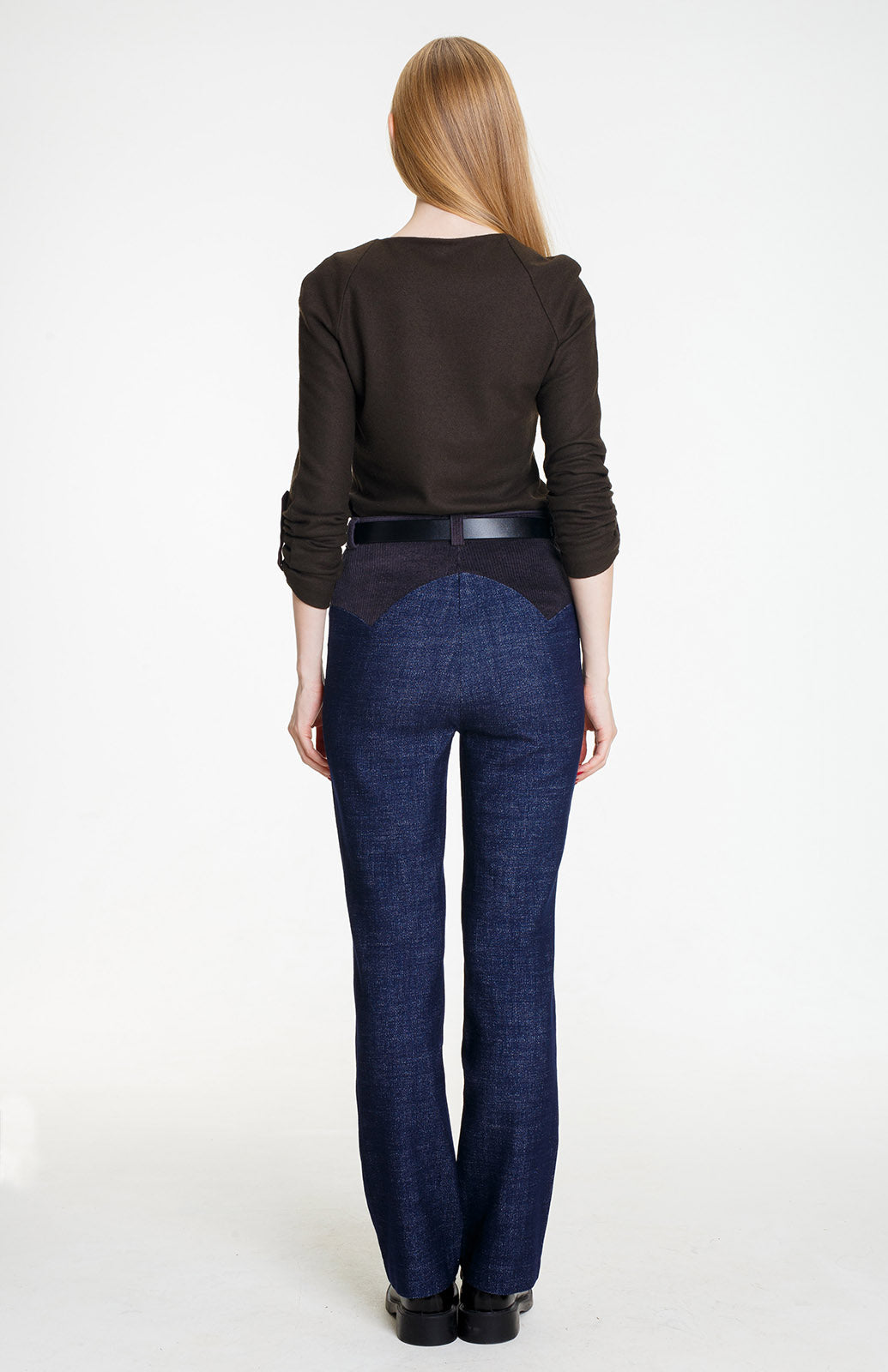 A full-length rear view of a woman wearing the straight-leg blue wool trousers. The back features a high-set, pointed anthracite yoke that creates a flattering, structured shape.