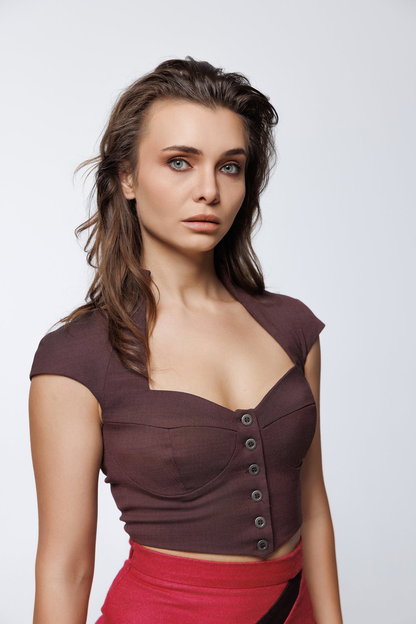 Close-up of metallic button detailing on a deep maroon wool-blend structured crop top.