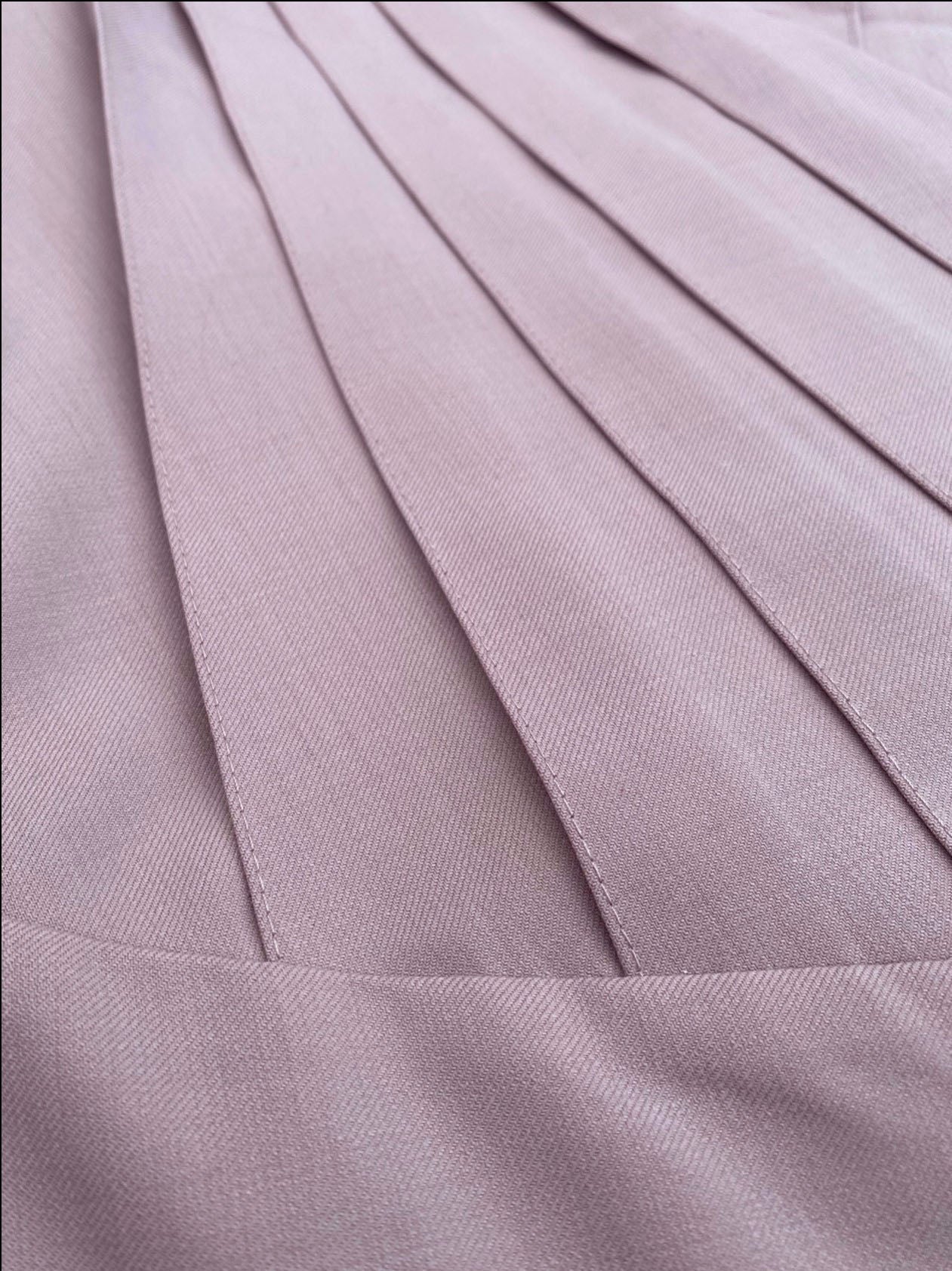 Macro view of pleated wrap front of a porcelain rose structured midi dress.