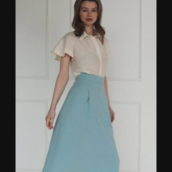 A studio video showing the ivory short‑sleeve silk–viscose blouse, highlighting the flared raglan sleeves, fluid drape, and soft sheen of the fabric.