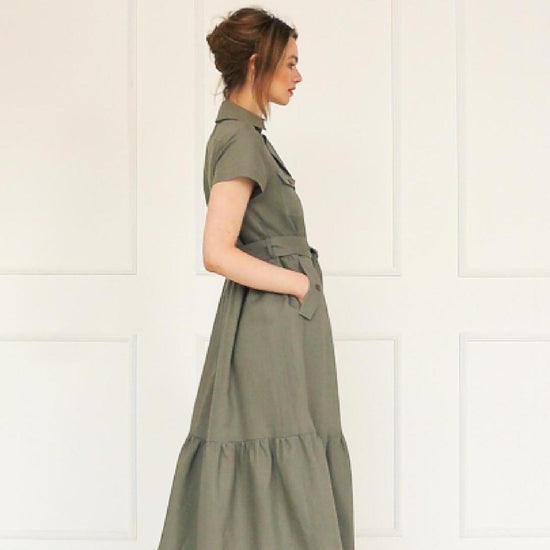 A studio video showing the model wearing  an olive green linen button‑down maxi dress, highlighting the belted waist, tiered hem, and the natural drape of the lightweight linen blend.
