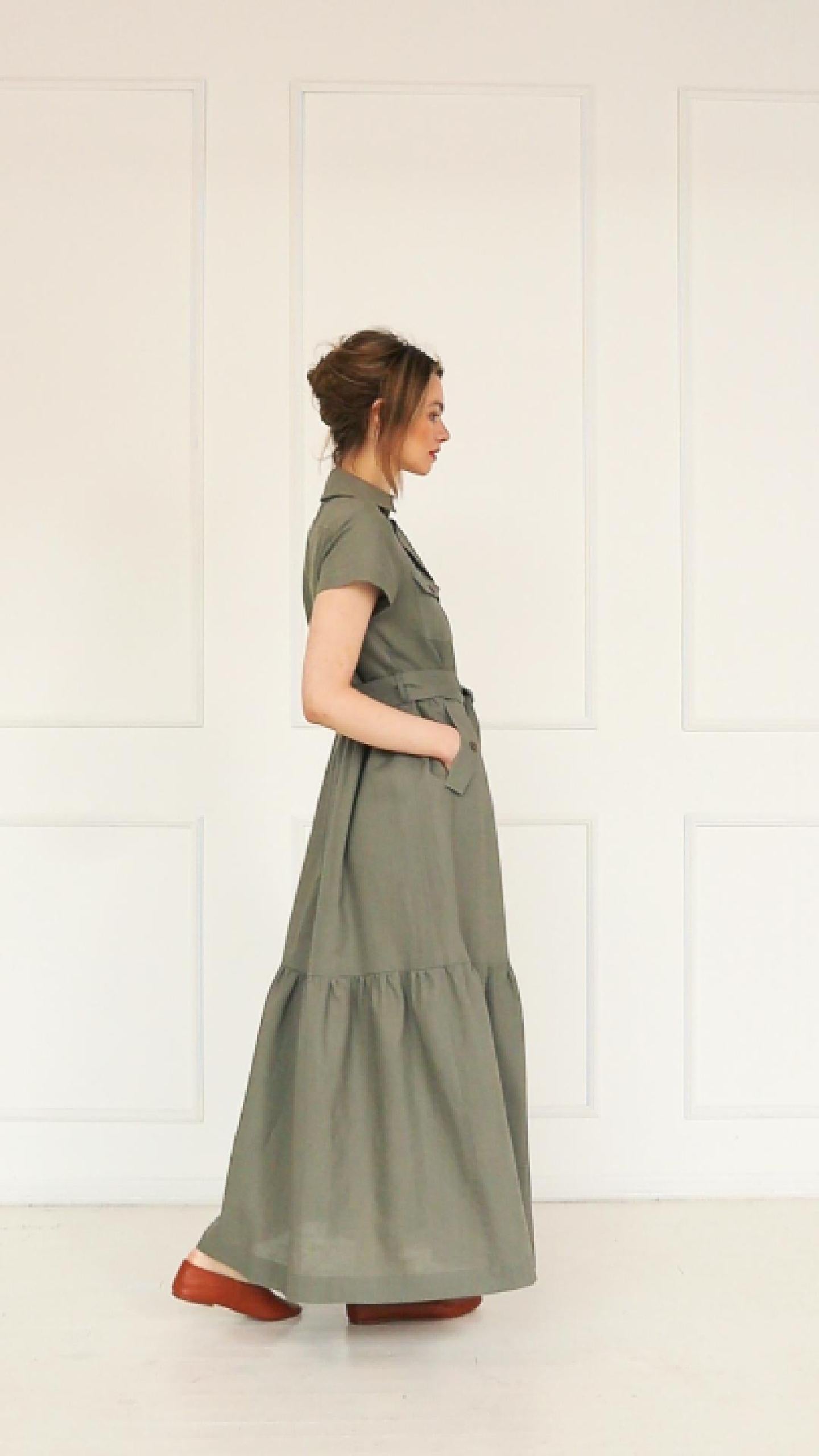 A studio video showing the model wearing  an olive green linen button‑down maxi dress, highlighting the belted waist, tiered hem, and the natural drape of the lightweight linen blend.