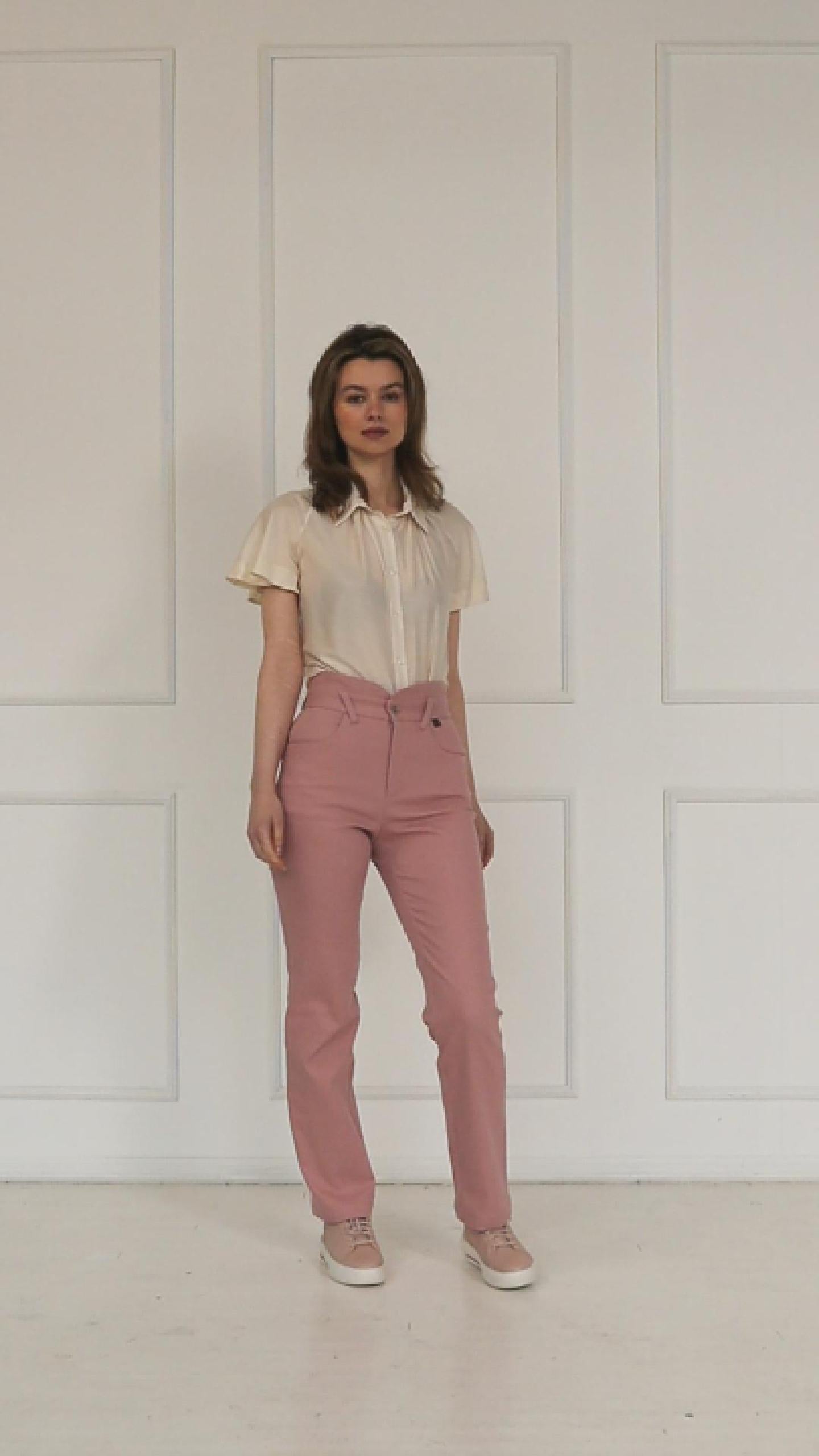 A studio video showing the rose‑dust high‑waisted stretch denim trousers, highlighting the layered waistband, tailored straight‑leg cut, and soft pastel finish.