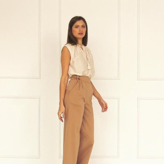 A studio video highlighting the adjustable side‑button waistband of the high‑waisted wide‑leg trousers, showing how the multi‑button fastening refines the fit and shapes the pleated front.