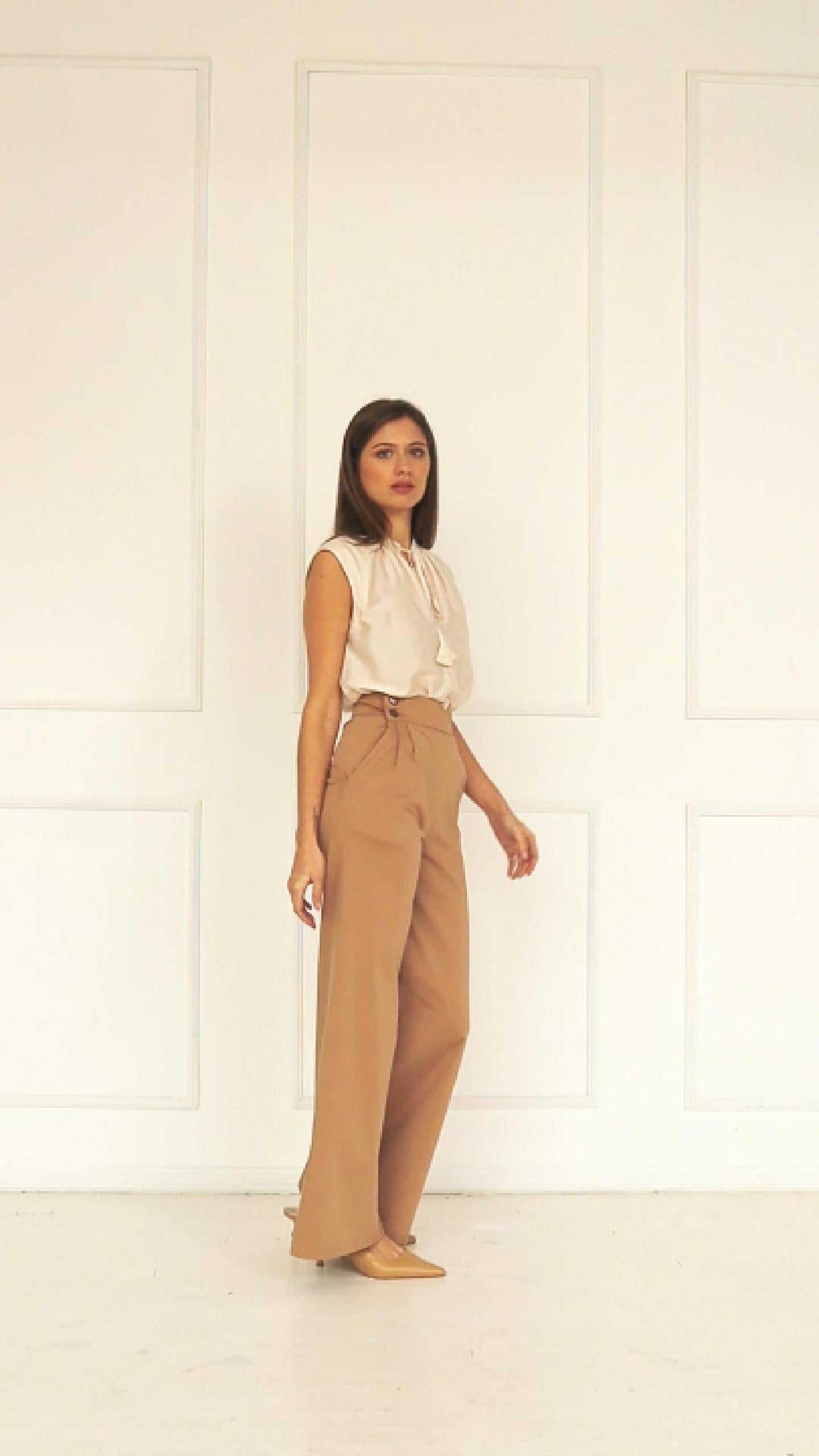 A studio video highlighting the adjustable side‑button waistband of the high‑waisted wide‑leg trousers, showing how the multi‑button fastening refines the fit and shapes the pleated front.