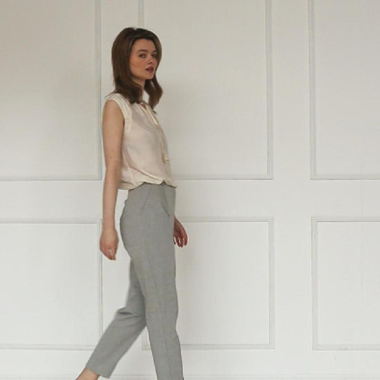 A studio video showing the light grey tapered carrot‑leg trousers in a cotton blend, highlighting the high‑waisted construction, clean front seam, and sculpted tapered silhouette.