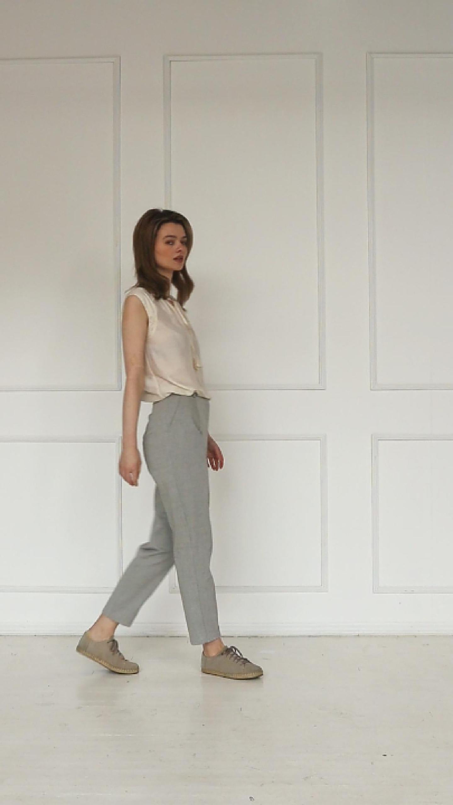 A studio video showing the light grey tapered carrot‑leg trousers in a cotton blend, highlighting the high‑waisted construction, clean front seam, and sculpted tapered silhouette.