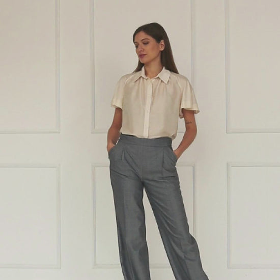 A studio video highlighting the adjustable side‑button waistband of the mid‑waisted wide‑leg virgin wool trousers, showing how the fastening refines the fit and shapes the tailored drape.