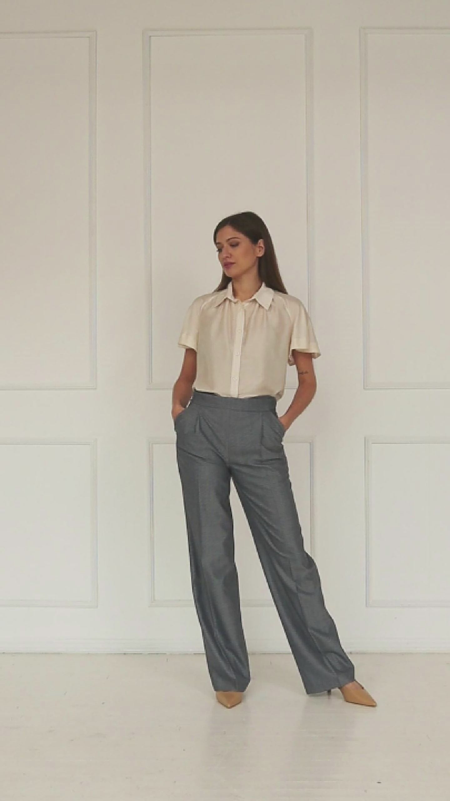 A studio video highlighting the adjustable side‑button waistband of the mid‑waisted wide‑leg virgin wool trousers, showing how the fastening refines the fit and shapes the tailored drape.